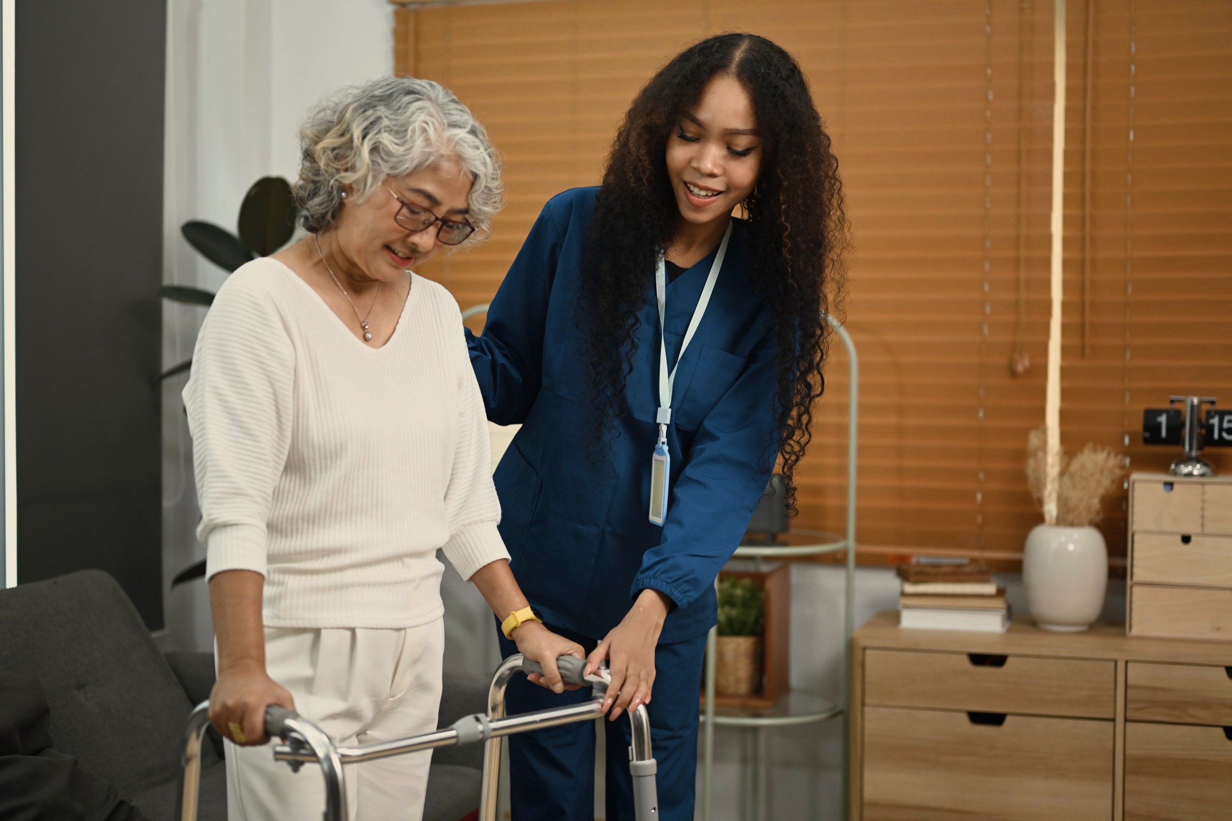A carer helping a resident up from a chair, both mid conversation
