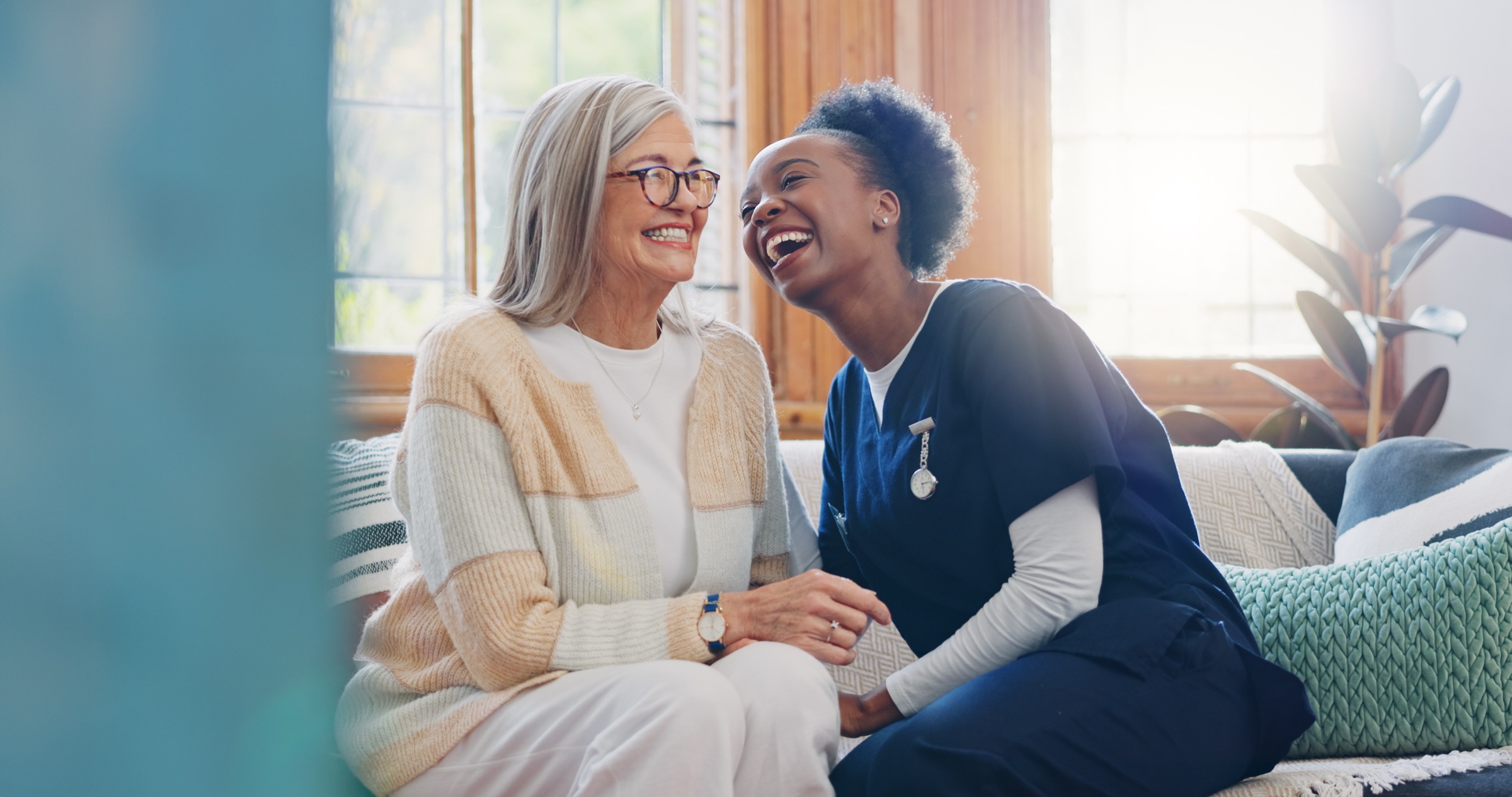 A carer and a resident laughing together on the sofa